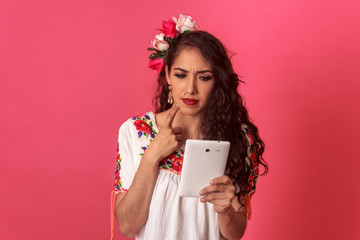 Mexicana latina en blusa bordada tradicional utilizando una tableta