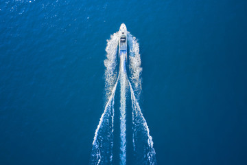 Drone view of a boat sailing. Top view of a white boat sailing to the blue sea. Motor boat in the...
