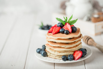 Classic american pancakes with fresh berry on white wood background. Summer homemade breakfast.
