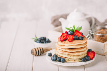Classic american pancakes with fresh berry on white wood background. Summer homemade breakfast.