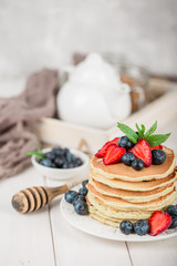 Classic american pancakes with fresh berry on white wood background. Summer homemade breakfast.