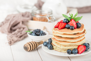 Classic american pancakes with fresh berry on white wood background. Summer homemade breakfast.