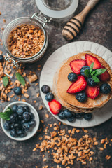 American pancakes with fresh berry and granola on metal background. Summer homemade breakfast.