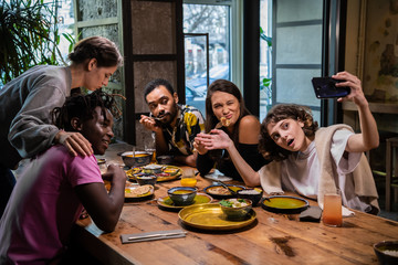 Group of young students making faces, taking pictures with their smartphone.