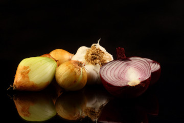 Onions and garlic over black background. Still-life of onions and falling garlic on black background