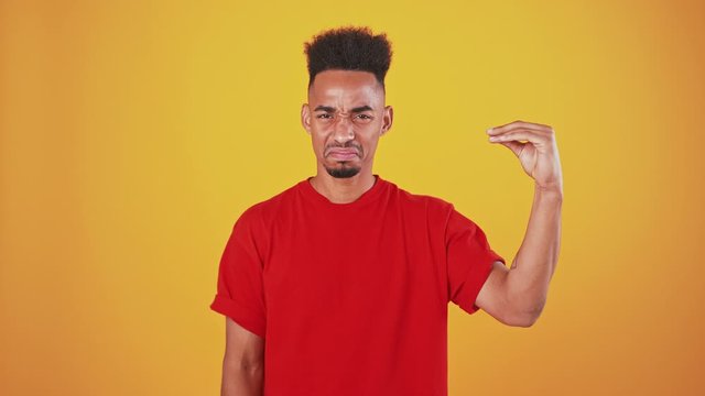African american man showing bla bla gesture with hand and shaking head no, orange studio background