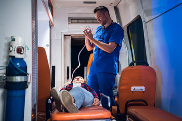 Medical student having an exam, preparing to give an oxygen mask to his patient in an ambulance car.