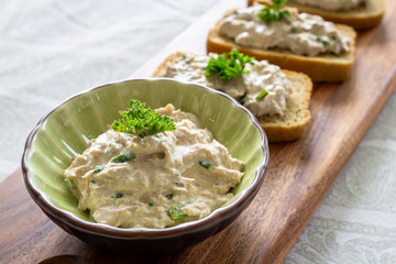 vista cerrada de tazon de dip de pollo junto a pan tostado sobre una tabla de madera decorativo