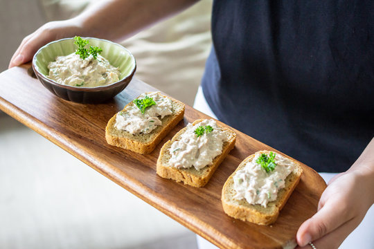 chica sosteniendo una bandeja de ensalada de crema blanca, lonjas de pan, comida casera