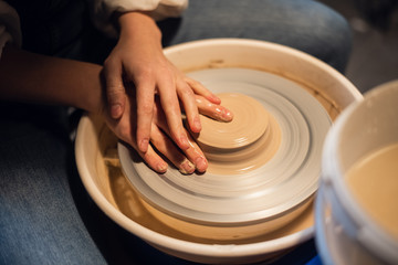 in the workshop, a Potter hands sculpts a vase from clay on a Potter's wheel