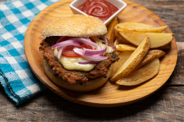 Tuna burger with potato fries on wooden background