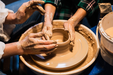 young mother and son sculpt clay dishes in a pottery workshop, close-up