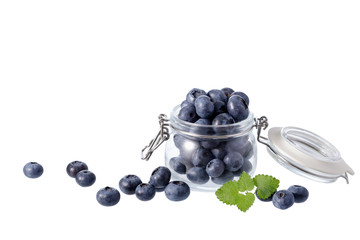 Fresh blueberry in glass jar and scattered with mint leaves isolated on white background