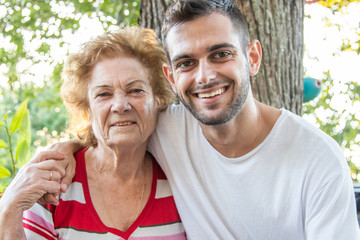 portrait of young man with happy grandmother smiling outdoors