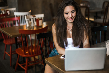 Business woman working on a laptop and drinking coffee in a cafe.