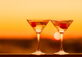 Martini drink at golden sunset background. Night life concept.