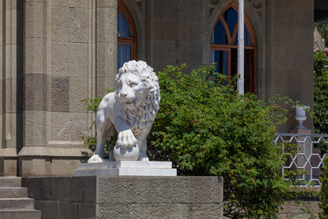 A stone sculpture of a lion with a paw on a ball stands at the entrance to an ancient castle