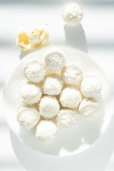 white chocolate coconut truffles on a plate against the backdrop of window shade. flat lay.