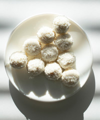 top view of white chocolate coconut truffles on a plate against the backdrop of window shade