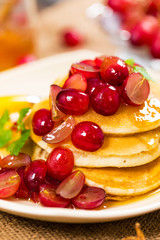 Stack of Pancakes with Sliced Red Grapes and Maple Syrup for breakfast. Selective focus.
