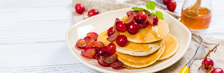 Stack of Pancakes with Sliced Red Grapes and Maple Syrup for breakfast. Selective focus.