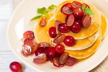 Stack of Pancakes with Sliced Red Grapes and Maple Syrup for breakfast. Selective focus.