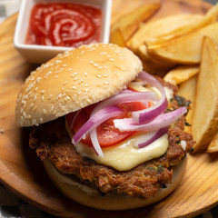 Tuna burger with potato fries on dark background