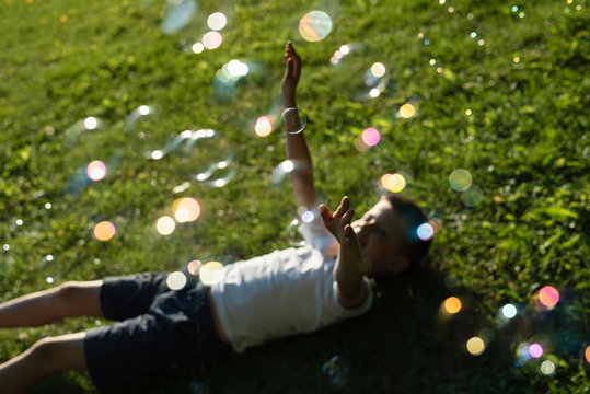 conceptual picture with soap bubbles, blurred focus, boy catching soap bubbles with his hands