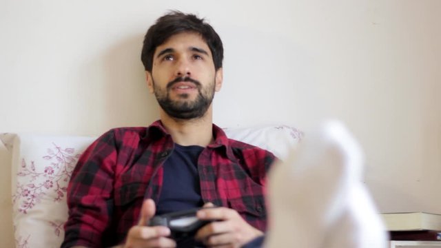 Handsome young millenial man playing fun video games in bed smiling and laughing