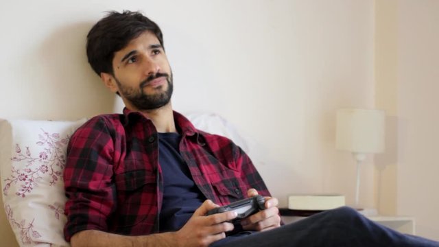 Handsome young millenial man playing video games in bed