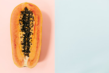 Papaya on a pastel pink blue background, creative food concept, tropical fruit. Flat lay. Top view. Tropical travel, exotic fruit. Vegan and vegetarian concept