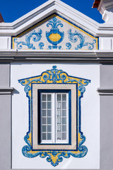 Window decorated with typical Portuguese tiles with geometric shapes and white, blue and yellow colors in Cascais, Portugal