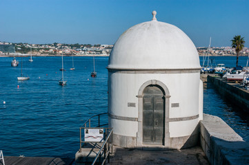View with sun of the Cascais tide gauge in Portugal, in front of the Tagus River
