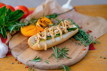 Barbecue grilled hot dog with yellow mustard and pepper sauce. Tomatoe and greens close up.