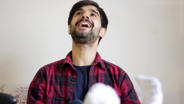 Handsome young millenial man playing video games in bed celebrating victory