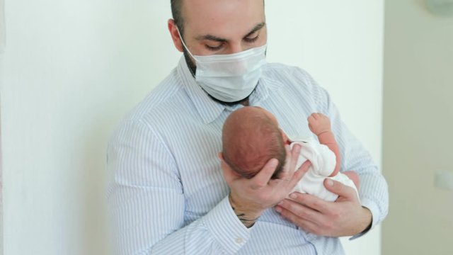 Happy father holding a crying newborn boy in the maternity ward