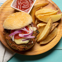 Tuna burger with potato fries on turquoise background