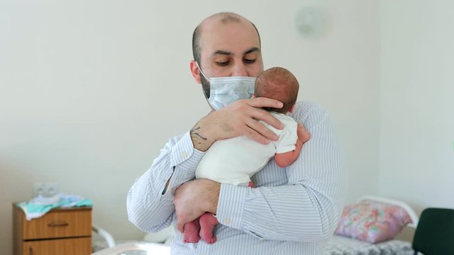 Happy father holding a crying newborn boy in the maternity ward