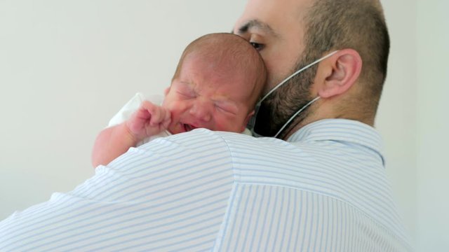 Happy father holding a crying newborn boy in the maternity ward