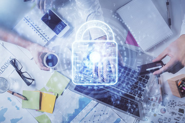 Multi exposure of man's hands typing over computer keyboard and lock hologram drawing. Top view. Technology concept.