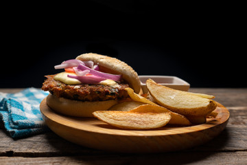Tuna burger with potato fries on wooden background