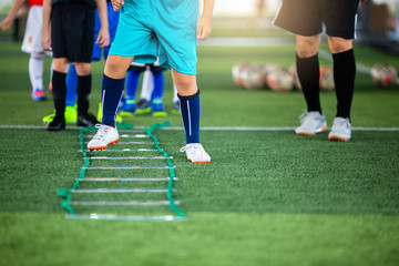 Fototapeta premium Kid soccer player Jogging and jump between marker for football training. Ladder Drills Exercises for Football team. Kid player exercises on ladder drills.