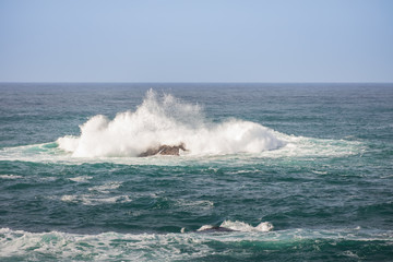 Waves breaking on large rock in ocean
