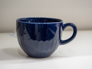 taza azul con fondo blanco y pared gris