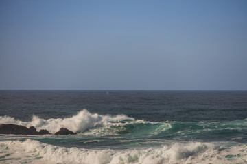Waves breaking on large rock in ocean