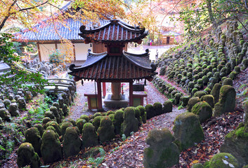 Old traditional pagoda in the centre of japanese garden with multiple stone statues.