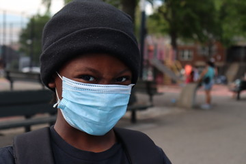 Child close up wearing surgical mask and skull cap hat outdoors
