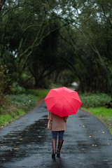 girl with red umbrella walking on a trail