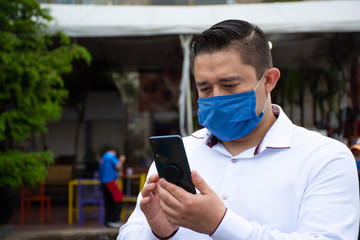Man with face mask uses his smartphone on the street
