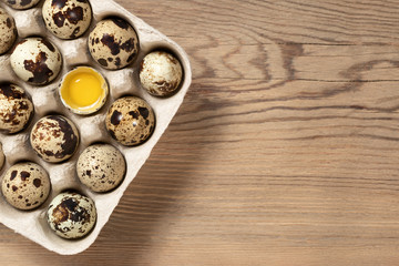 Quail eggs in cardboard packaging on a wooden table close-up, copy space,, flatlay
